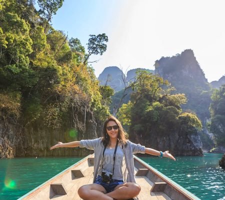 Asian woman relishing a serene boat journey through the lush karst landscape of Thailand's Khlong Sok.